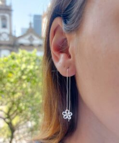 Mulher usando brinco de prata tipo flor