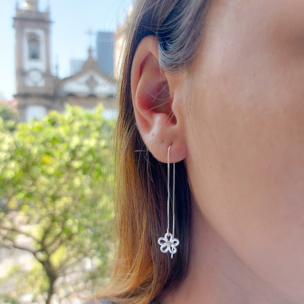 Mulher usando brinco de prata tipo flor