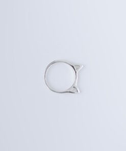 Anel de prata tipo gatinha sobre uma superfície branca e lisa