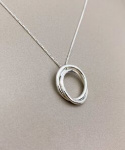 Foto próxima do Colar de prata Nó de Marinheiro sobre uma superfície lisa de cor escura