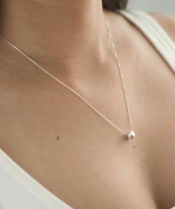 Modelo feminina de camiseta branca usando um Colar Bola Lisa de um ângulo diferente