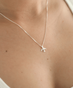 Modelo feminina de camiseta branca usando um colar Aviãozinho foto com zoom