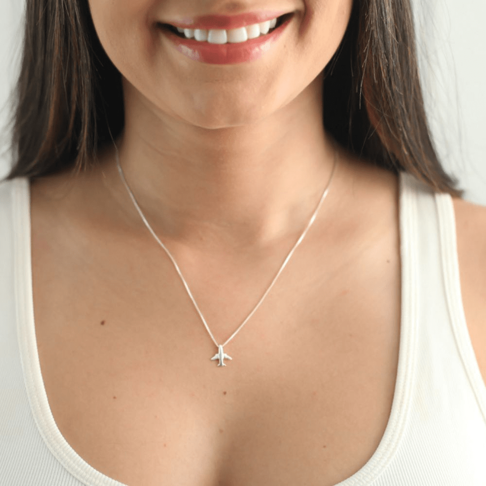 Modelo feminina de camiseta branca usando um colar Aviãozinho