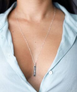 Moça jovem de blusa azul usando um colar Fases da Lua