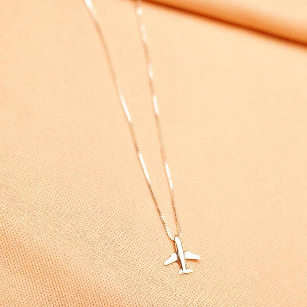 Foto do colar “Colar Aviãozinho”, acima de uma base de tecido