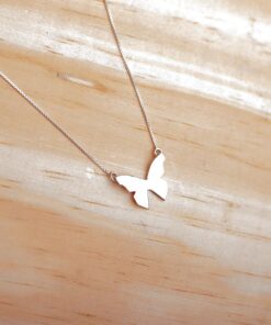 Foto do colar “Borboleta Origami”, acima de uma base de madeira rústica