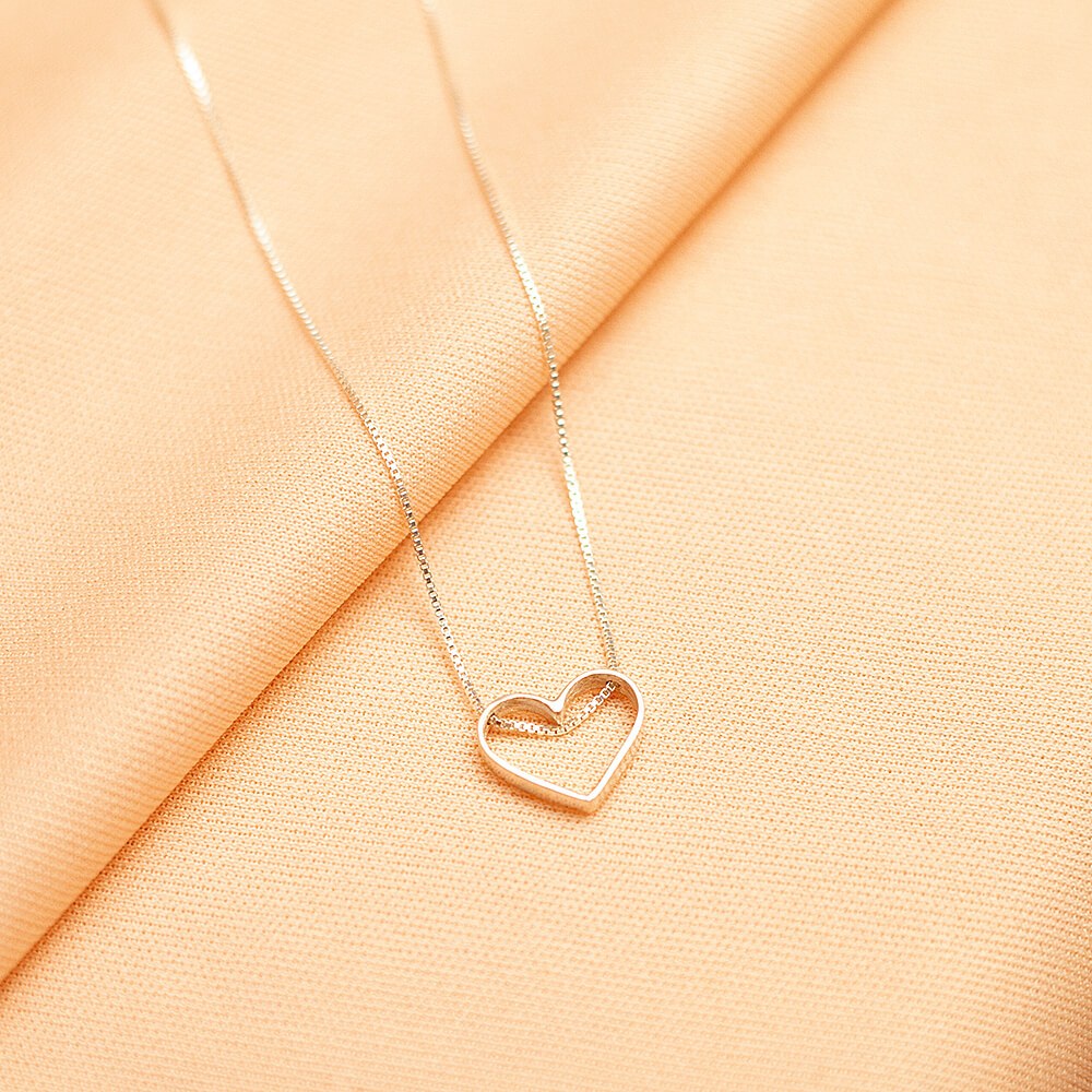 Foto do colar “Coração vazado”, acima de uma base de tecido