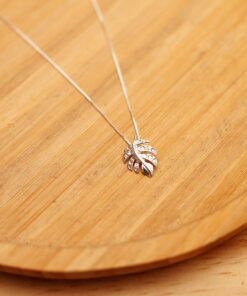 Foto do colar “Costela de Adão”, acima de uma base de madeira rústica