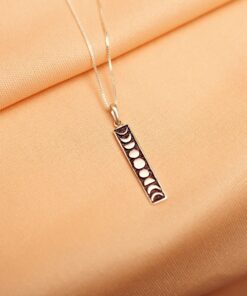 Foto do colar “Fases da Lua”, acima de uma base de tecido