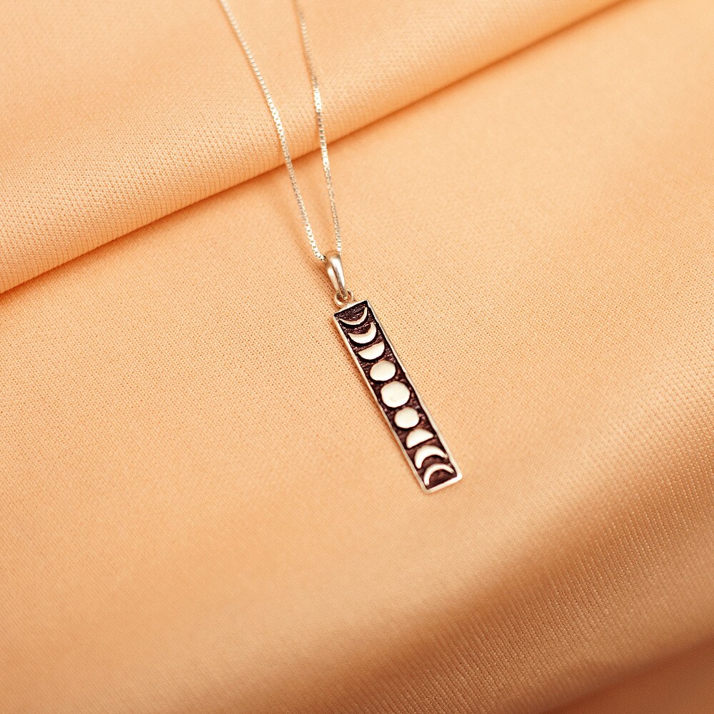 Foto do colar “Fases da Lua”, acima de uma base de tecido