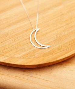 Foto do colar "Lua Vazada", acima de uma base de madeira rústica