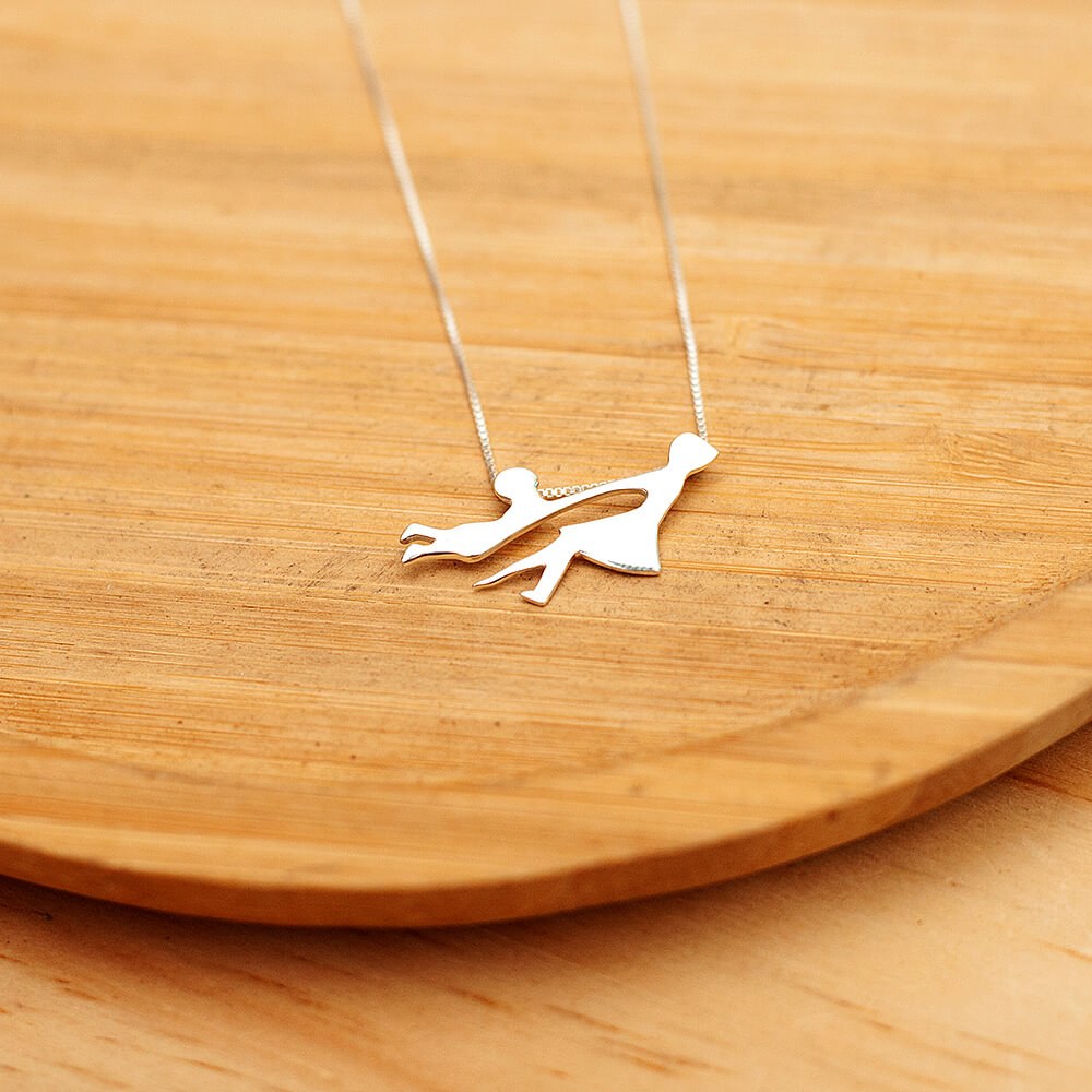 Foto do colar “Mãe e Filho”, acima de uma base de madeira rústica