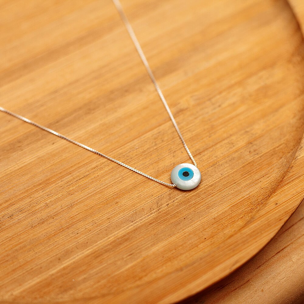 Foto do "Colar Olho grego", acima de uma base de madeira rústica