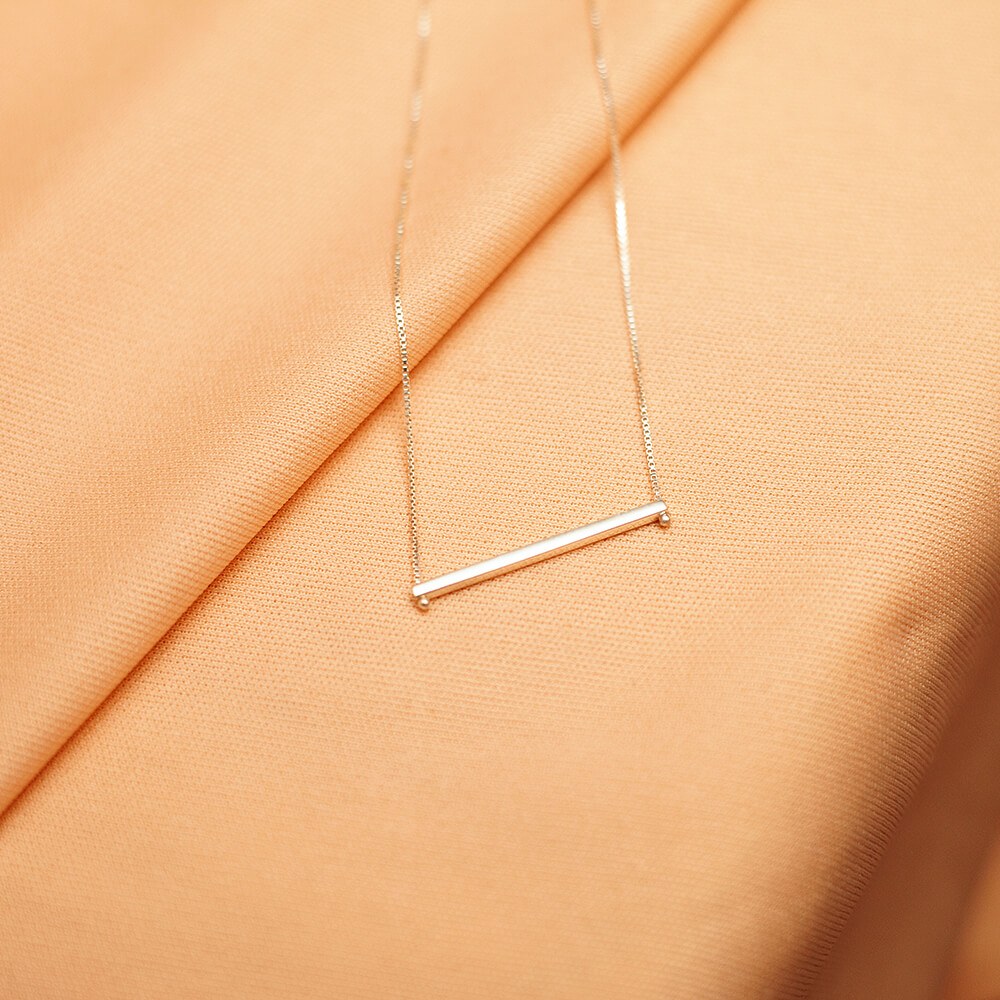 Foto do colar “Taquinho deitado”, acima de uma base de tecido