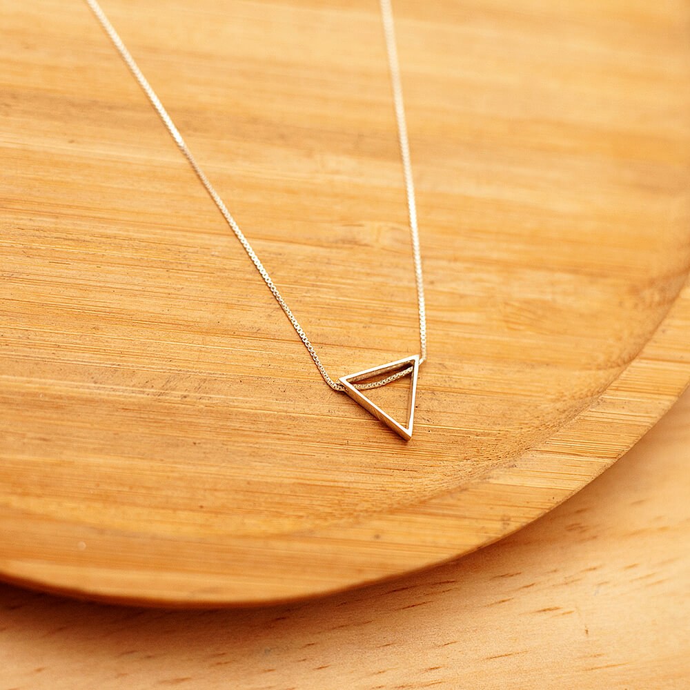 Foto do Colar Triangulo 3D acima de uma base de madeira rústica
