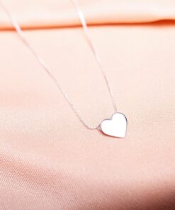 Foto do colar “coração chapa”, acima de uma base de tecido