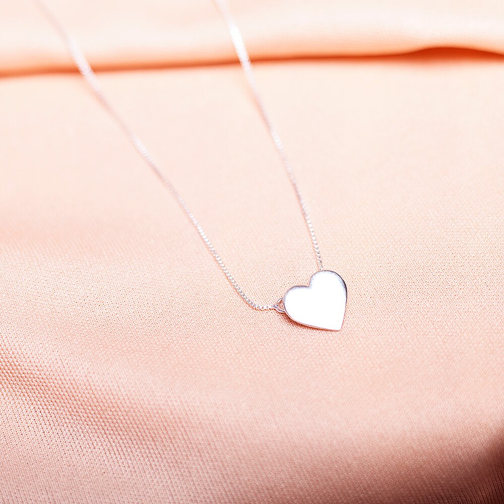 Foto do colar “coração chapa”, acima de uma base de tecido