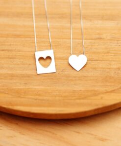 Foto do colar “Escapulário Coração Cartinha”, acima de uma base de madeira rústica