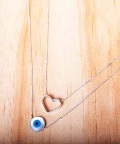 Foto do Escapulário “Coração e Olho Grego1”, acima de uma base de madeira rústica