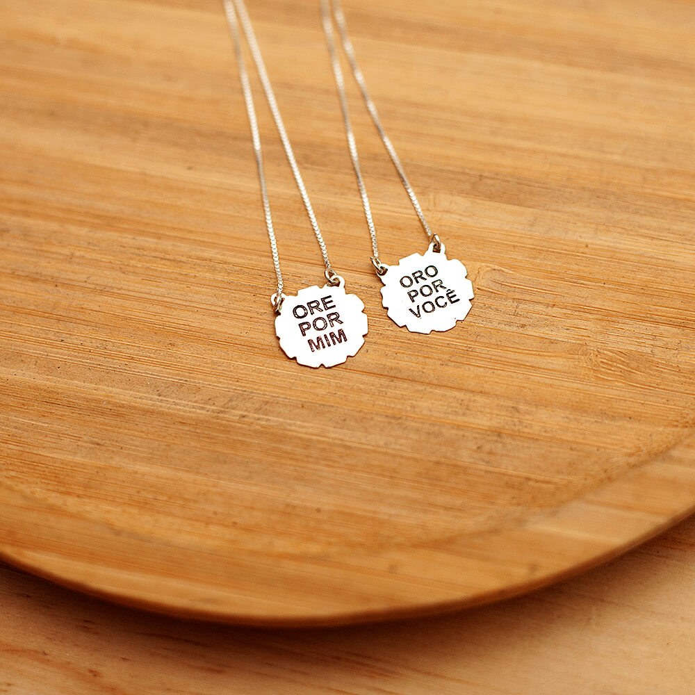 Foto do colar “Escapulário Ore por Mim”, acima de uma base de madeira rústica