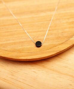 Colar de prata Agata negra sobre uma peça de madeira