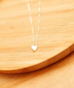 colar coração de prata 925 em um prato de madeira