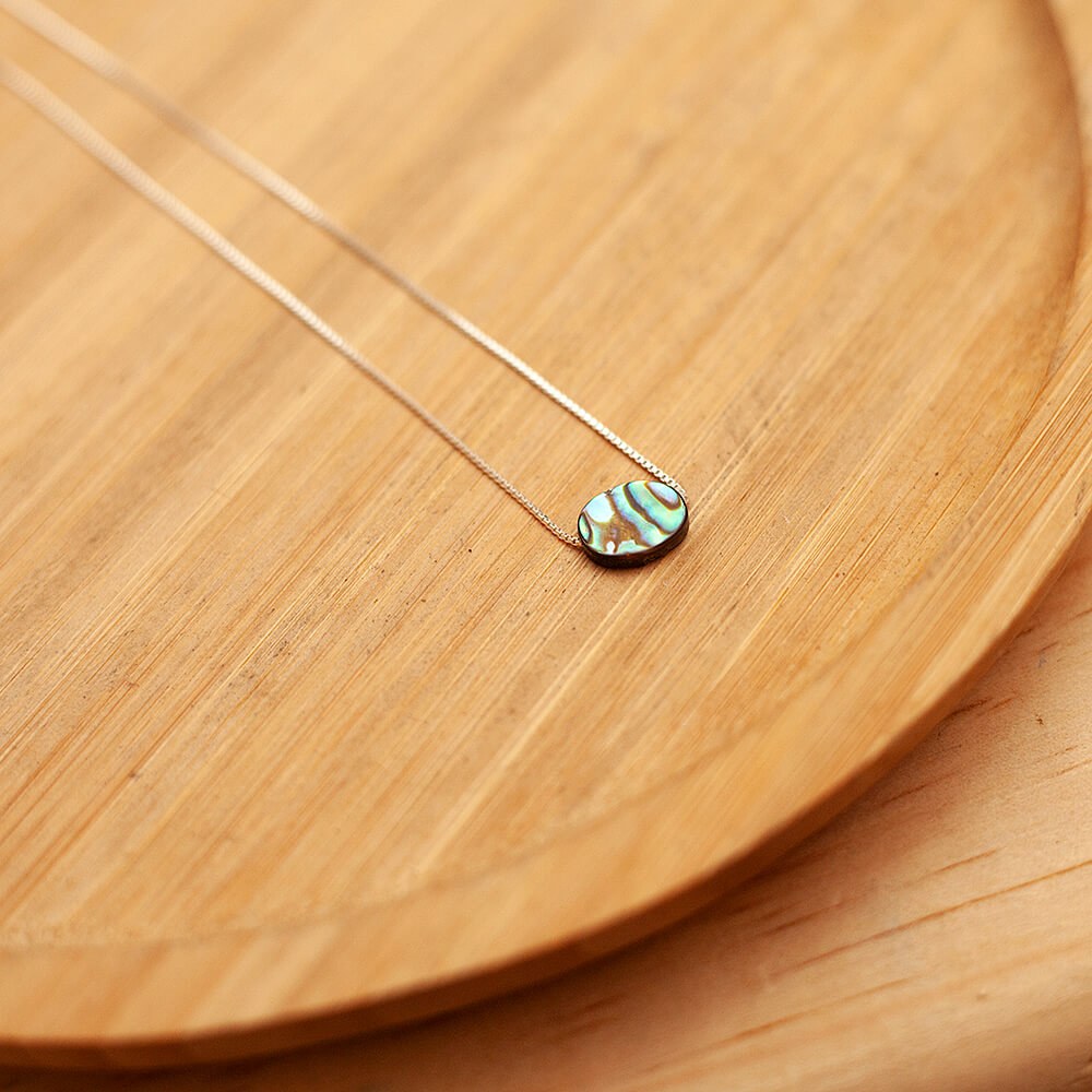 colar pedra abalone sobre prato de madeira