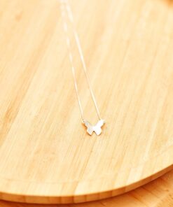 Colar borboleta de prata 925 sobre um prato de madeira