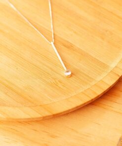 Colar de prata 925 taquinho ponto de luz sobre um prato de madeira