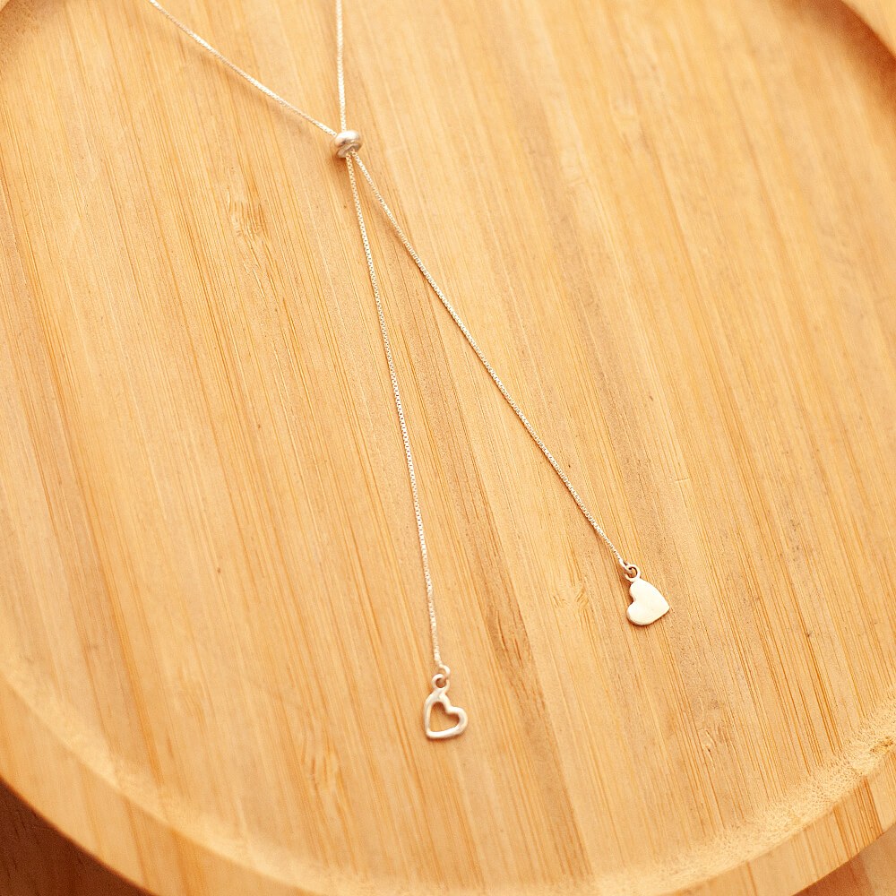 Gravatinha de corações em prata 925 sobre um prato de madeira