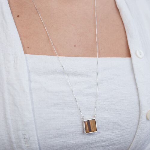 Modelo feminina usando Escapulario Olho de Tigre e Onix Quadrado de prata 925