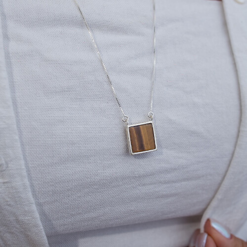 Modelo feminina usando Escapulario Olho de Tigre e Onix Quadrado de prata 925