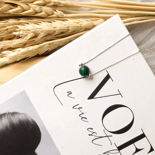 colar bola malaquita em livro com capa branca